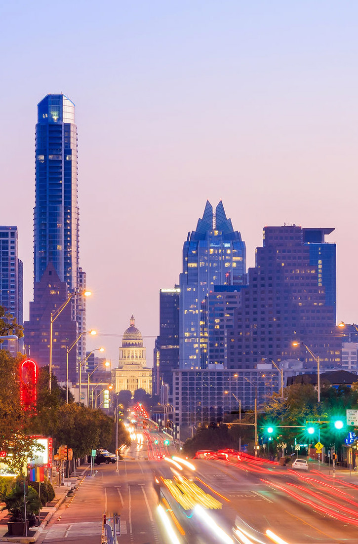 The capitol building is visible between skyscrapers in Austin, Texas.