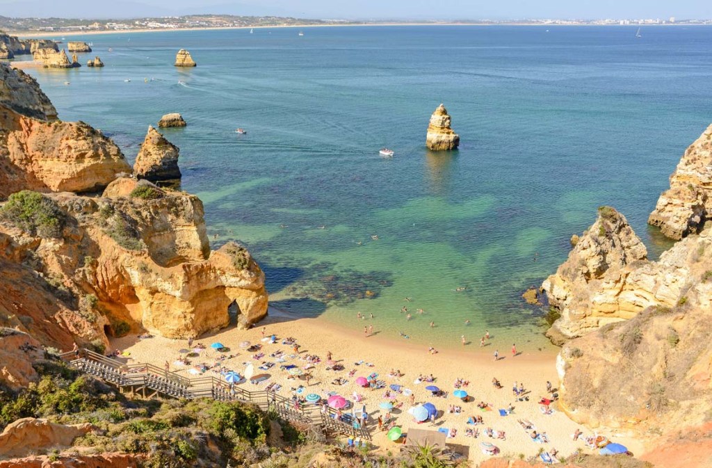 View looking down onto a beach with cliffs on either side, looking out toward the ocean.