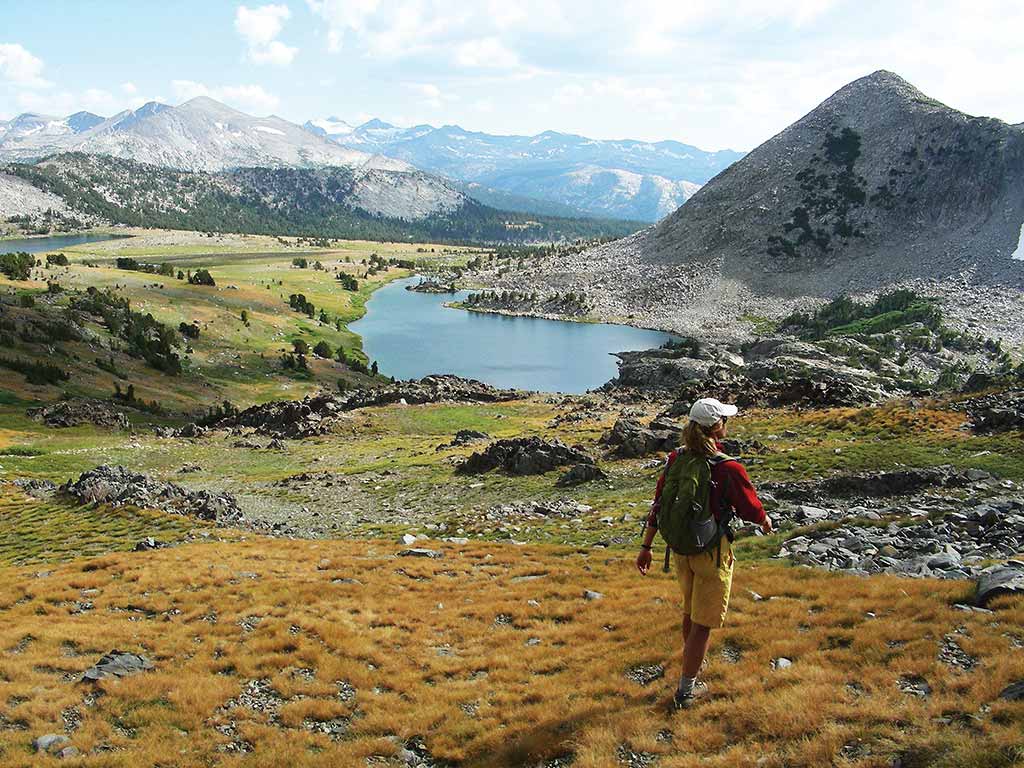 hiker approaching a lake in mountainous landscape