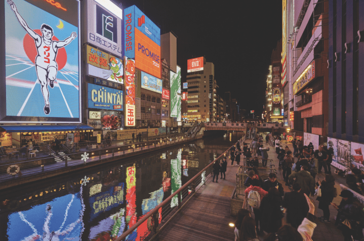 brightly lit neon displays on the side of buildings at night in dotombori